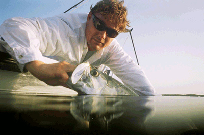 Captain Scott Irvine holds up a tarpon to reveal its reflection in the calm water off Key West